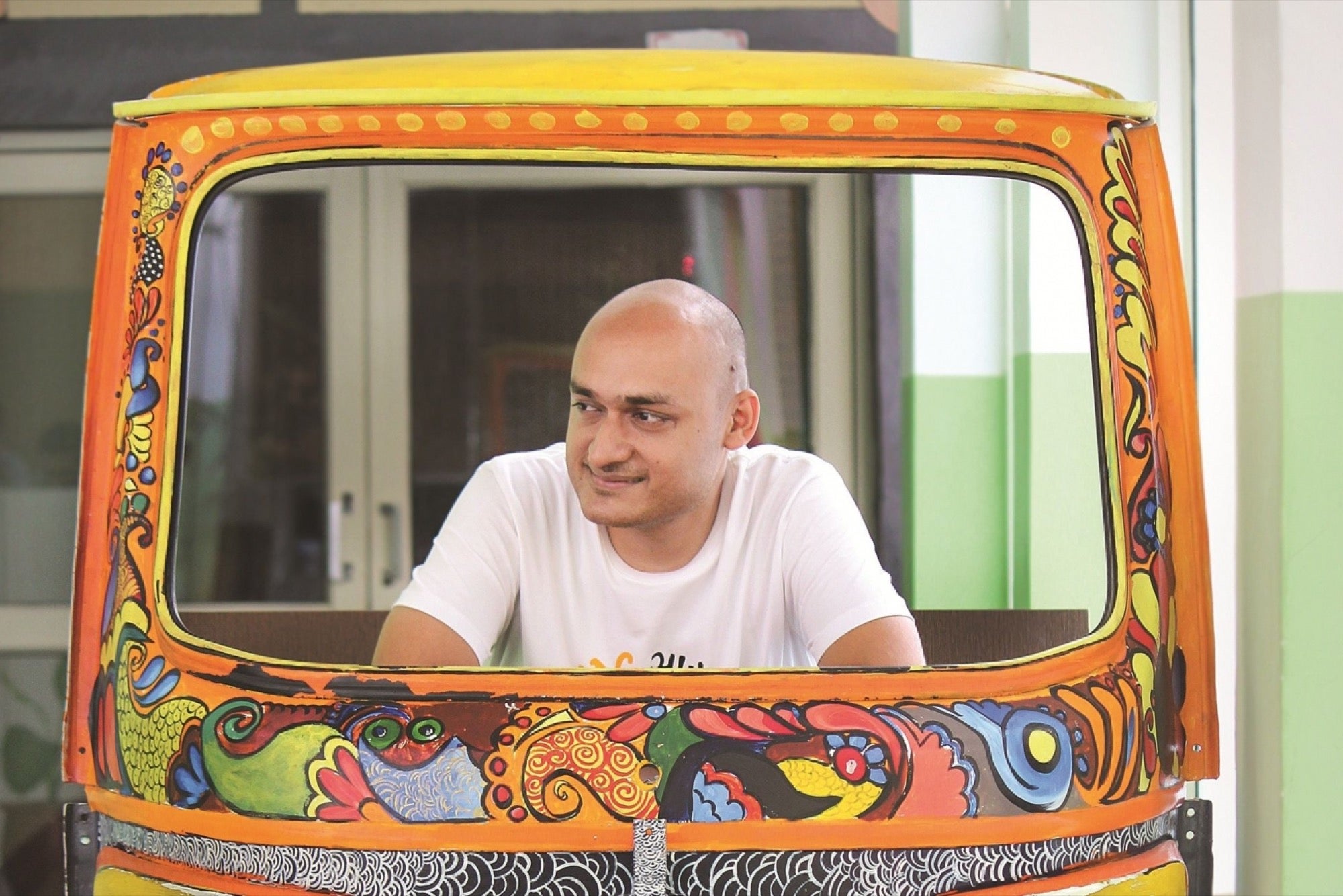 Samar Singla seated behind a brightly painted auto-rickshaw-shaped frame