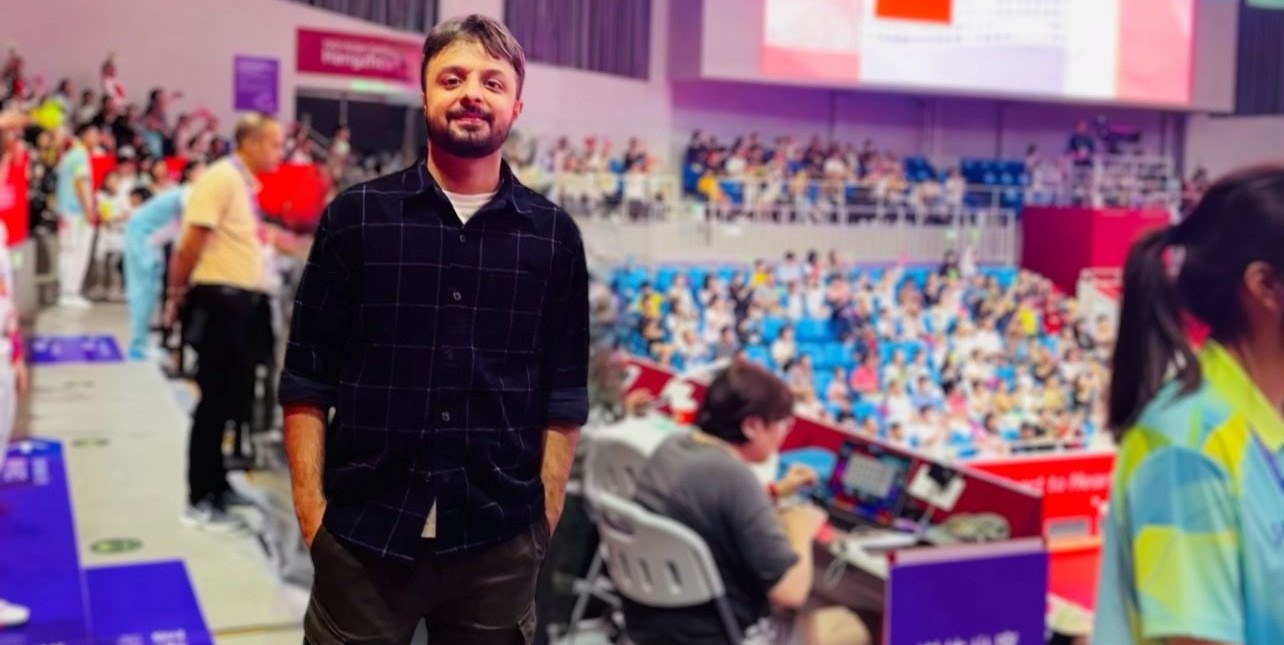 Sameer Sadana standing in an event venue with tiered seating behind him
