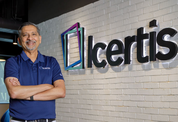 Samir Bodas standing beside the Icertis name on an office wall