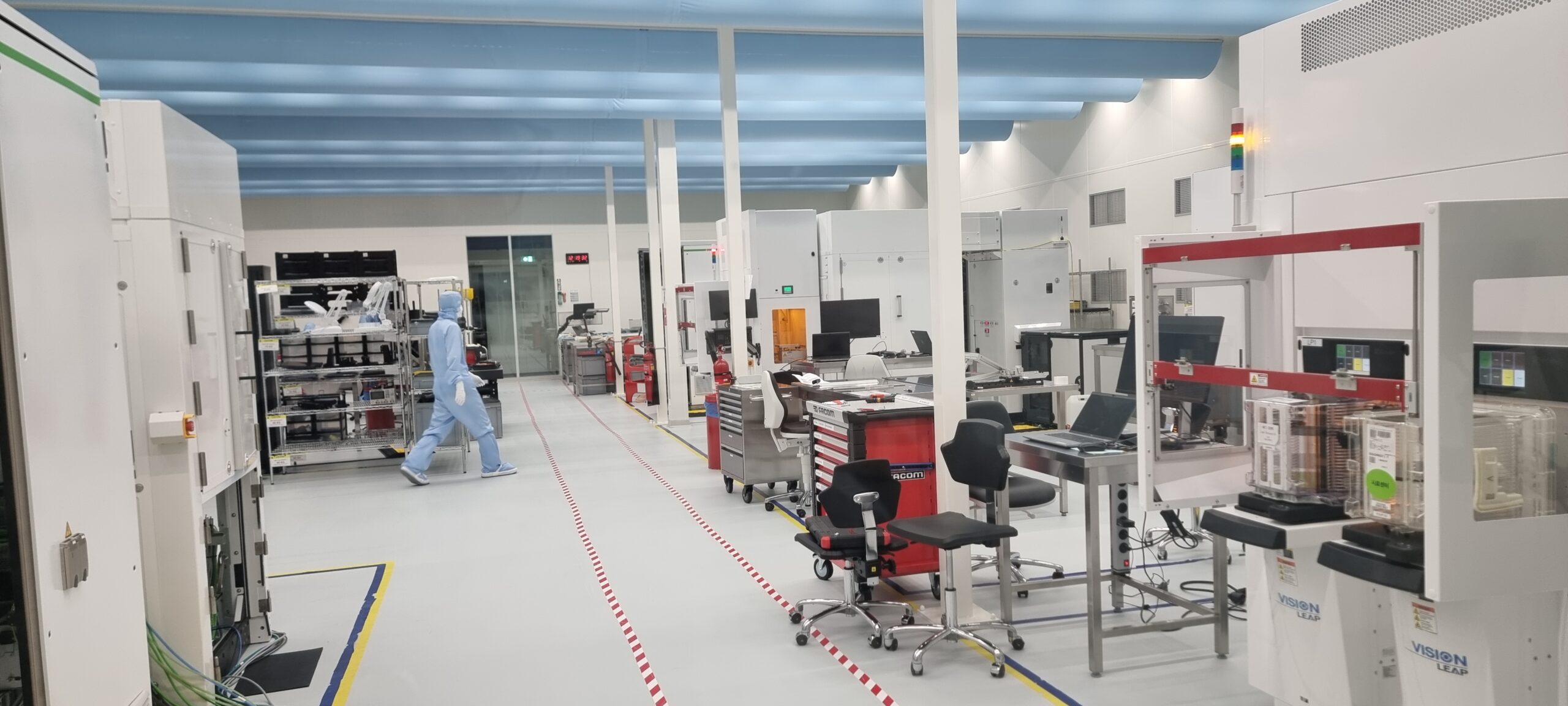 Nearfield Instruments cleanroom with large metrology systems and a worker in protective clothing