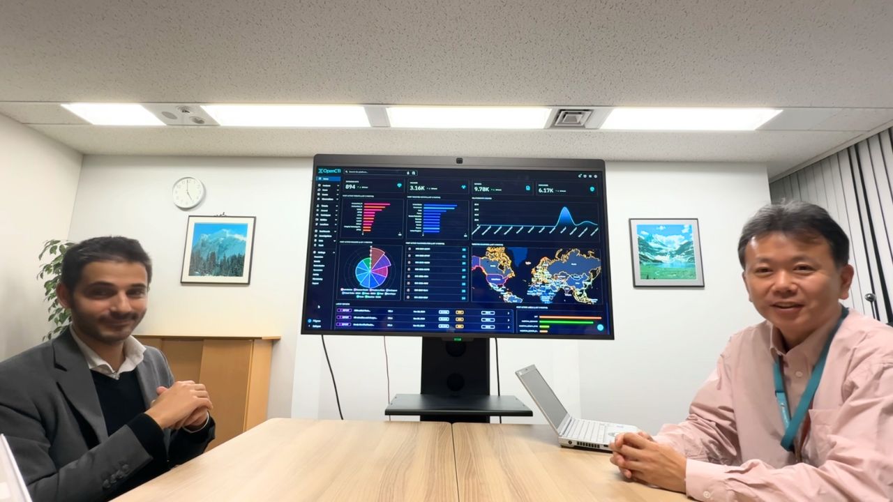 Samuel Hassine, left, speaking with Nobuo Miyamura beside a screen displaying OpenCTI