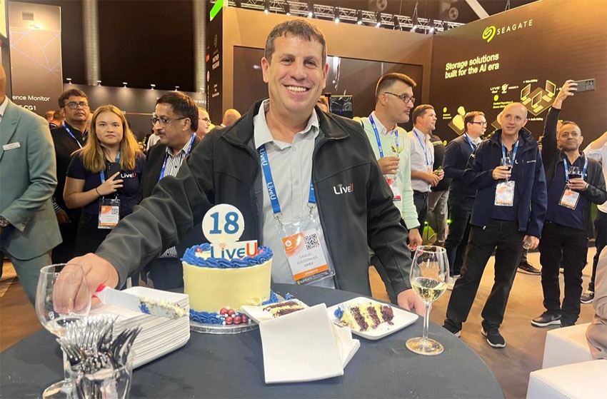 Samuel Wasserman smiling beside LiveU’s 18th-anniversary cake at IBC 2024
