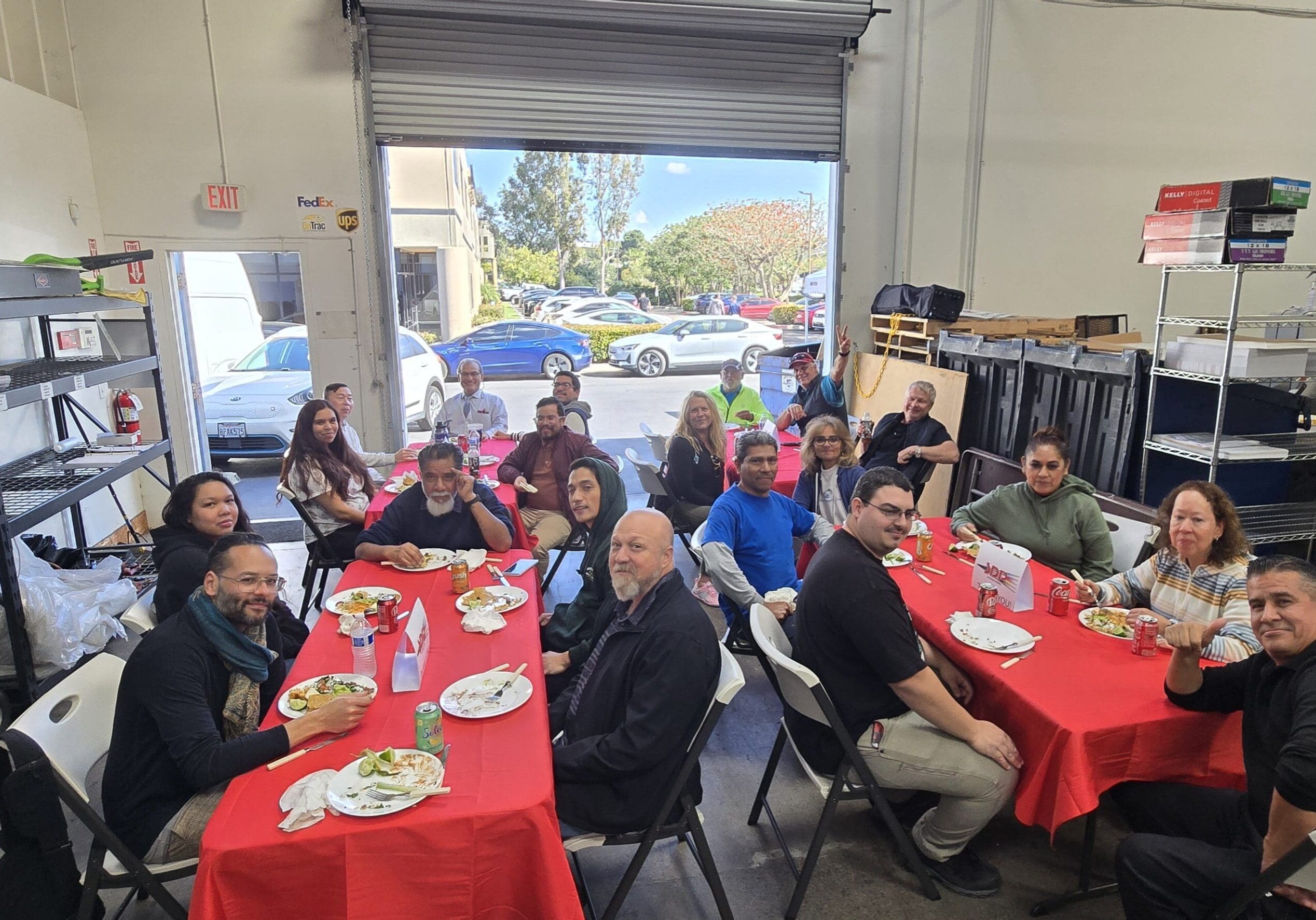 San Diego Printers employees sharing lunch at red-covered tables among warehouse shelving on February 13, 2026