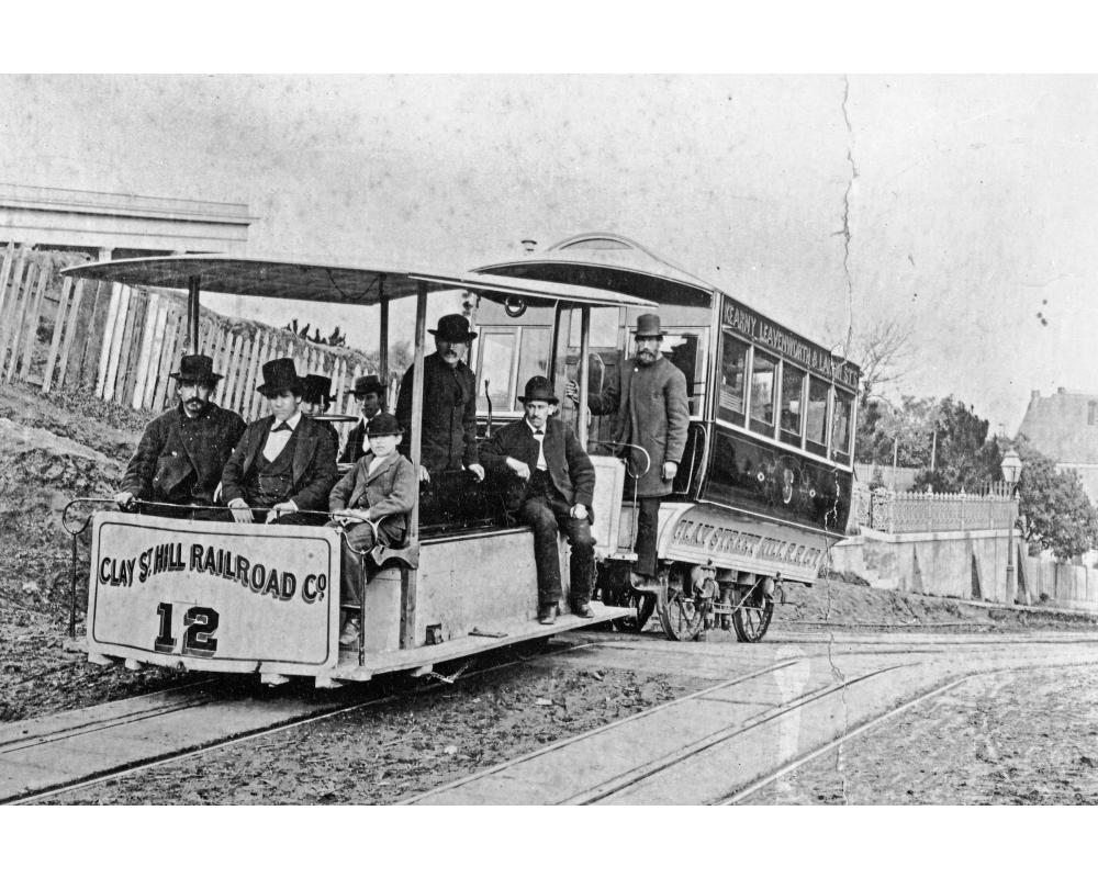 Andrew Hallidie stands on an early Clay Street cable car crowded with passengers in 1873