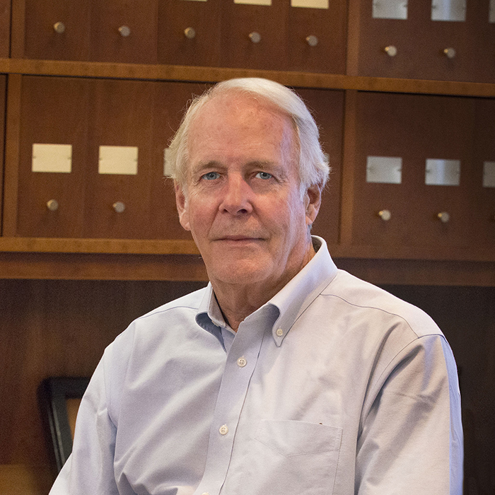 Sanderling founder Robert G. McNeil seated in front of wooden cabinetry
