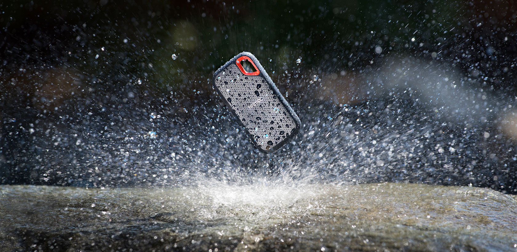 An earlier-generation Sandisk Extreme Portable SSD photographed amid a splash of water