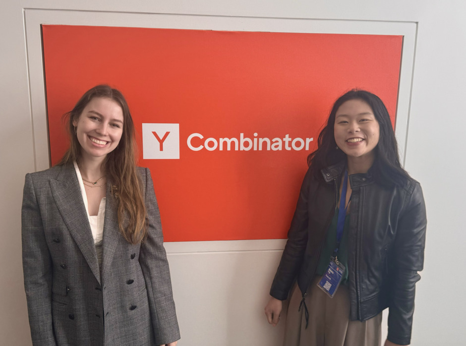 Sandra Lifshits and Maddy Yip standing beside a Y Combinator sign