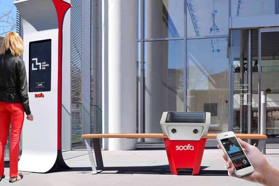A Soofa solar-powered charging bench beside a digital information sign