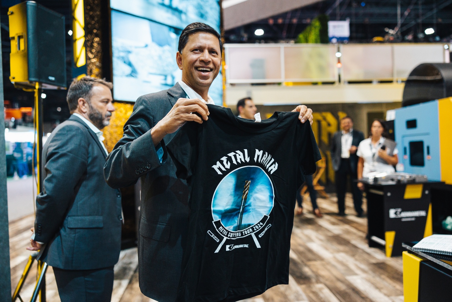 Sanjay Chowbey smiling and holding a Metal Mania T-shirt at Kennametal's IMTS 2024 booth