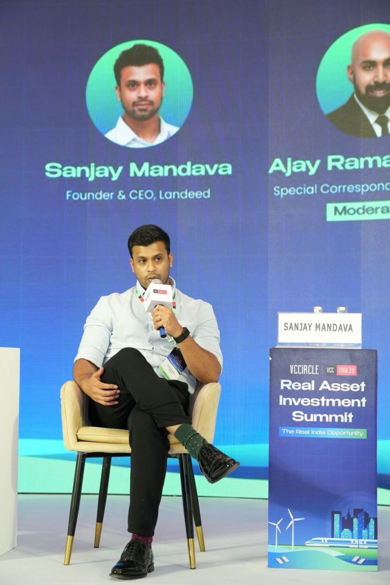 Sanjay Mandava seated onstage speaking into a microphone at the VCCircle Real Asset Investment Summit
