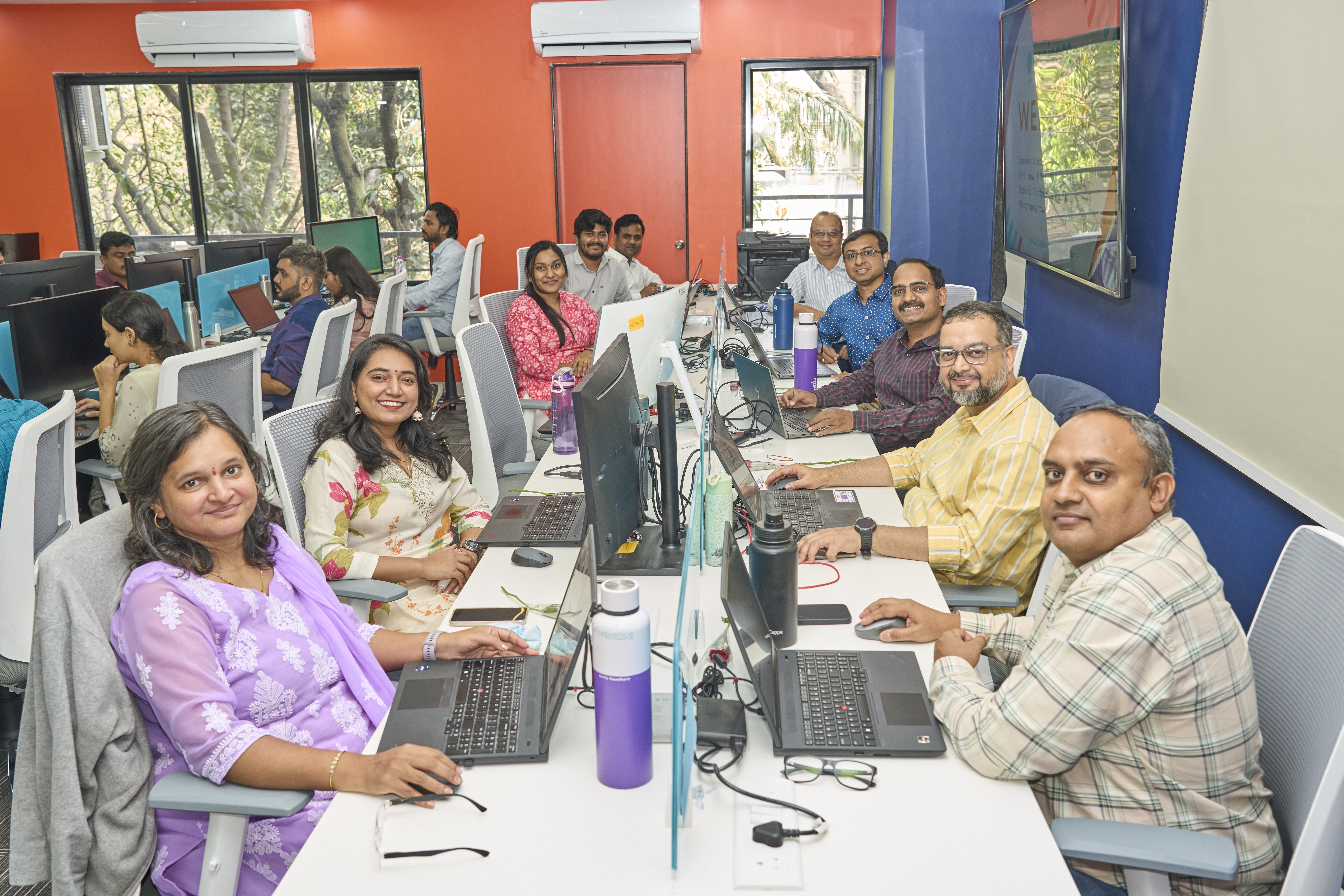 Sapience colleagues seated at shared desks in a colorful office