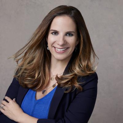 Sarah Guckes in a blue top and dark blazer, photographed with her arms crossed