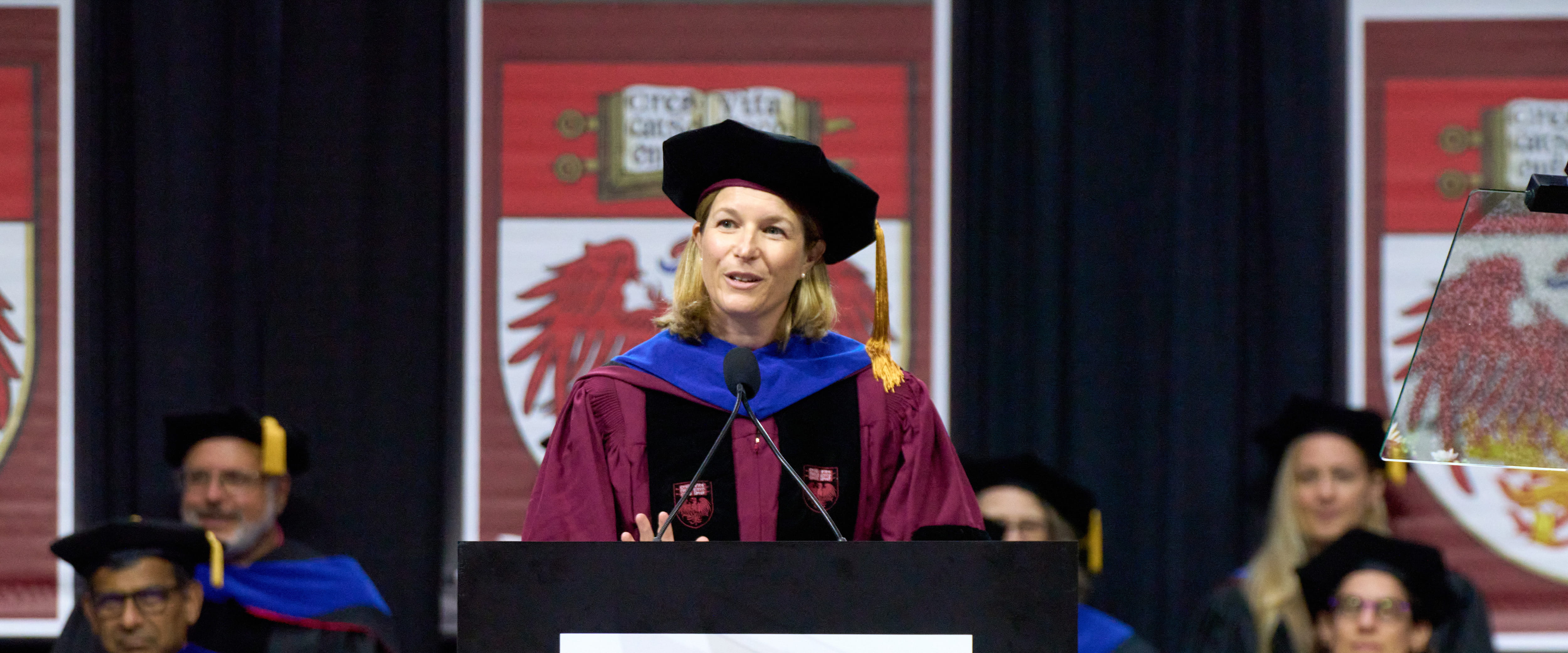 Sarah London in academic regalia delivering a speech at Chicago Booth’s 2024 graduation