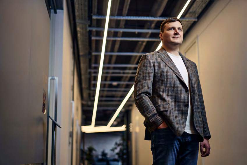 Sasha Strozhemin standing in an office corridor, wearing a checked blazer