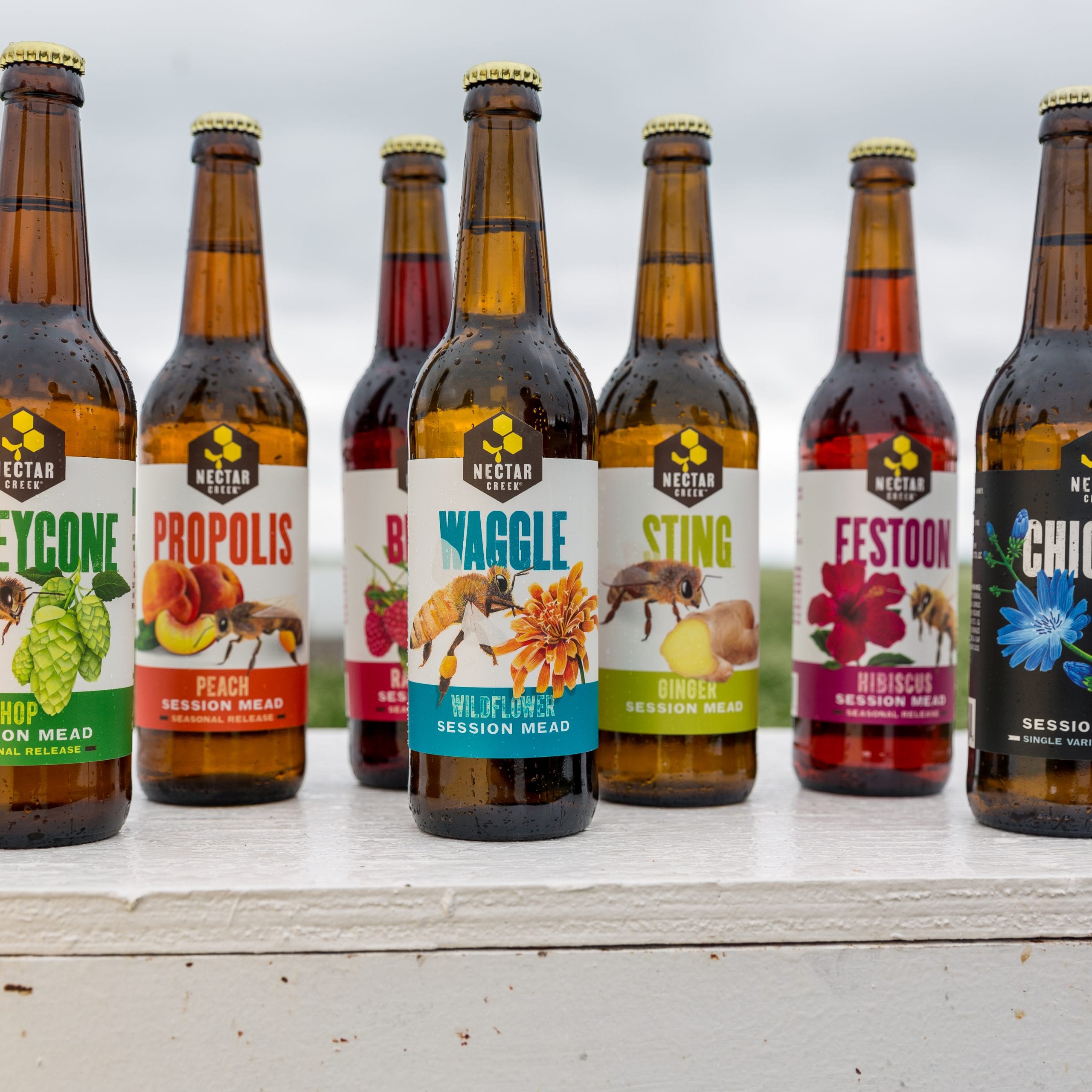 A lineup of colorful Nectar Creek bottles with illustrated labels
