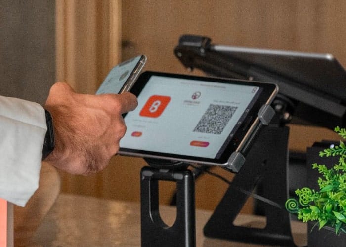 A customer uses a phone beside Bonat’s customer-facing screen at a checkout
