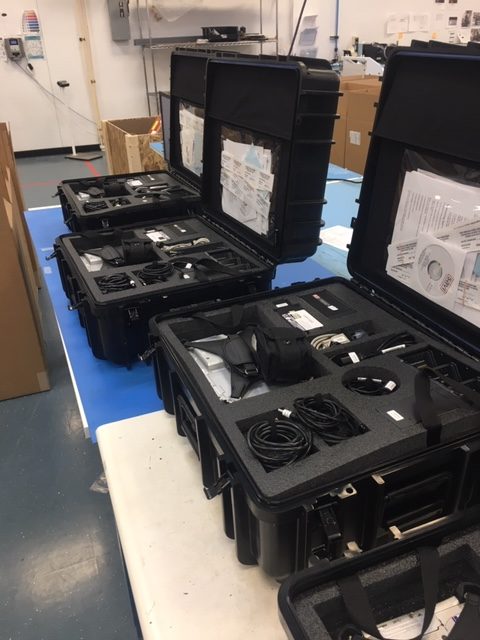 Three open black Savi PDK III equipment cases on an assembly table