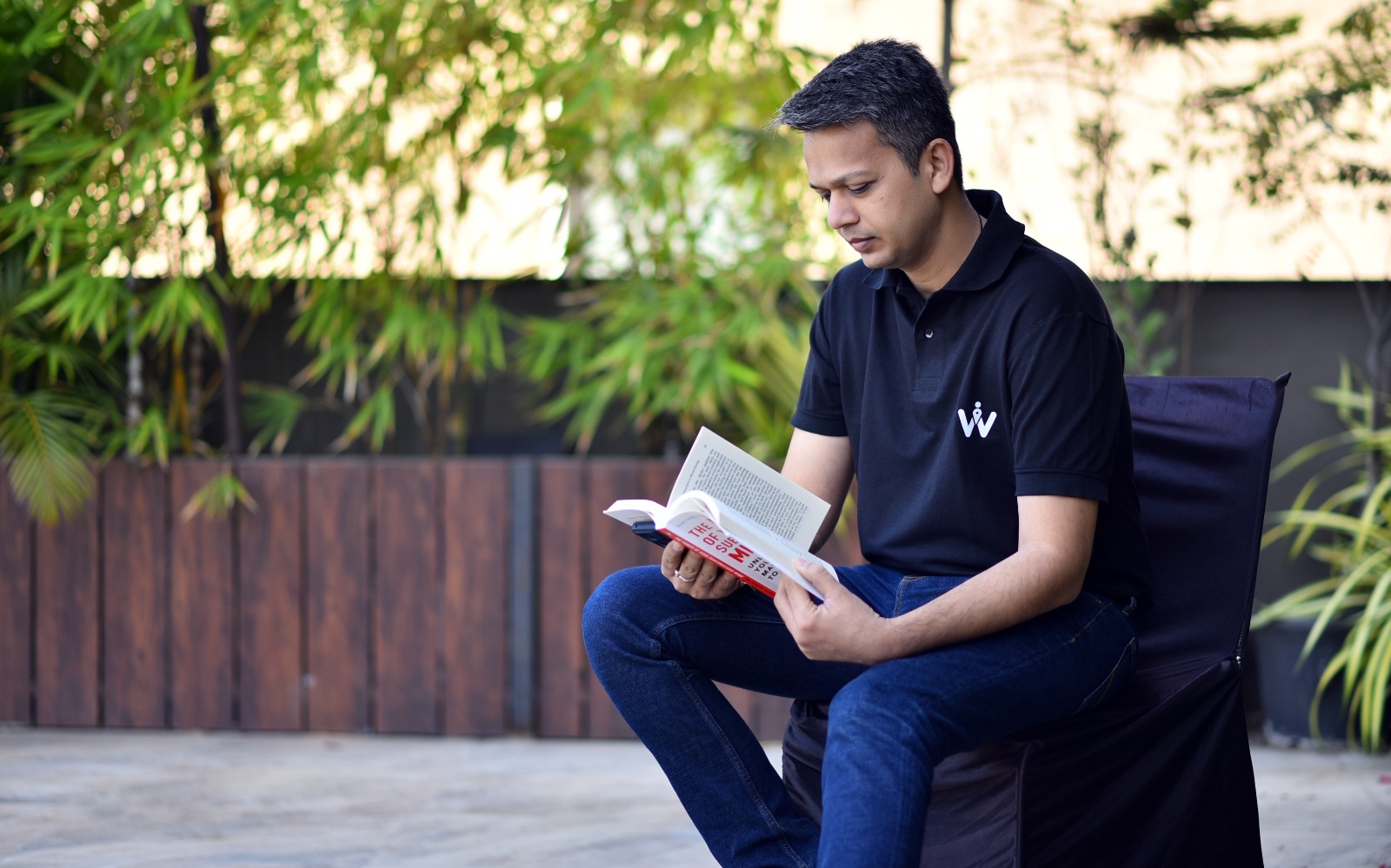Sawan Laddha seated outdoors reading an open book