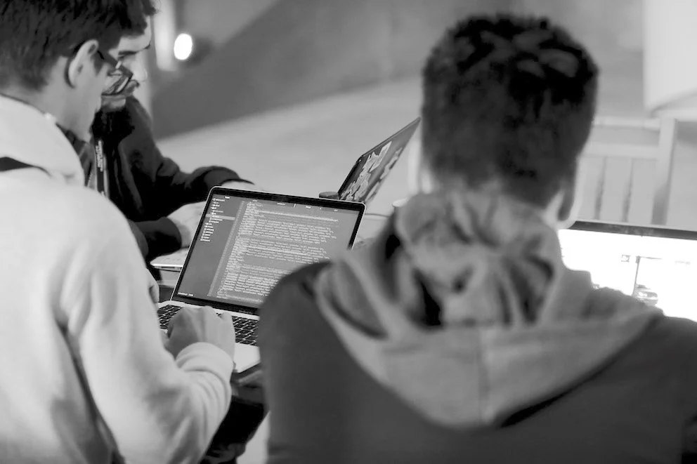 Participants working together on laptops in an event photograph published by SBI Consulting