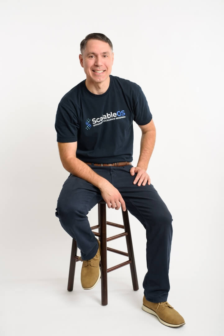 ScalableOS founder Chris Van Vladricken seated on a stool, wearing the company shirt