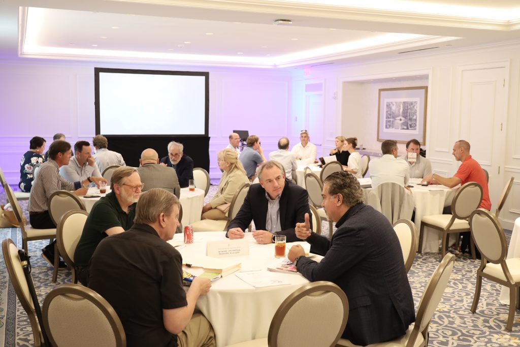 Participants talk around tables at a gathering pictured by SCbio