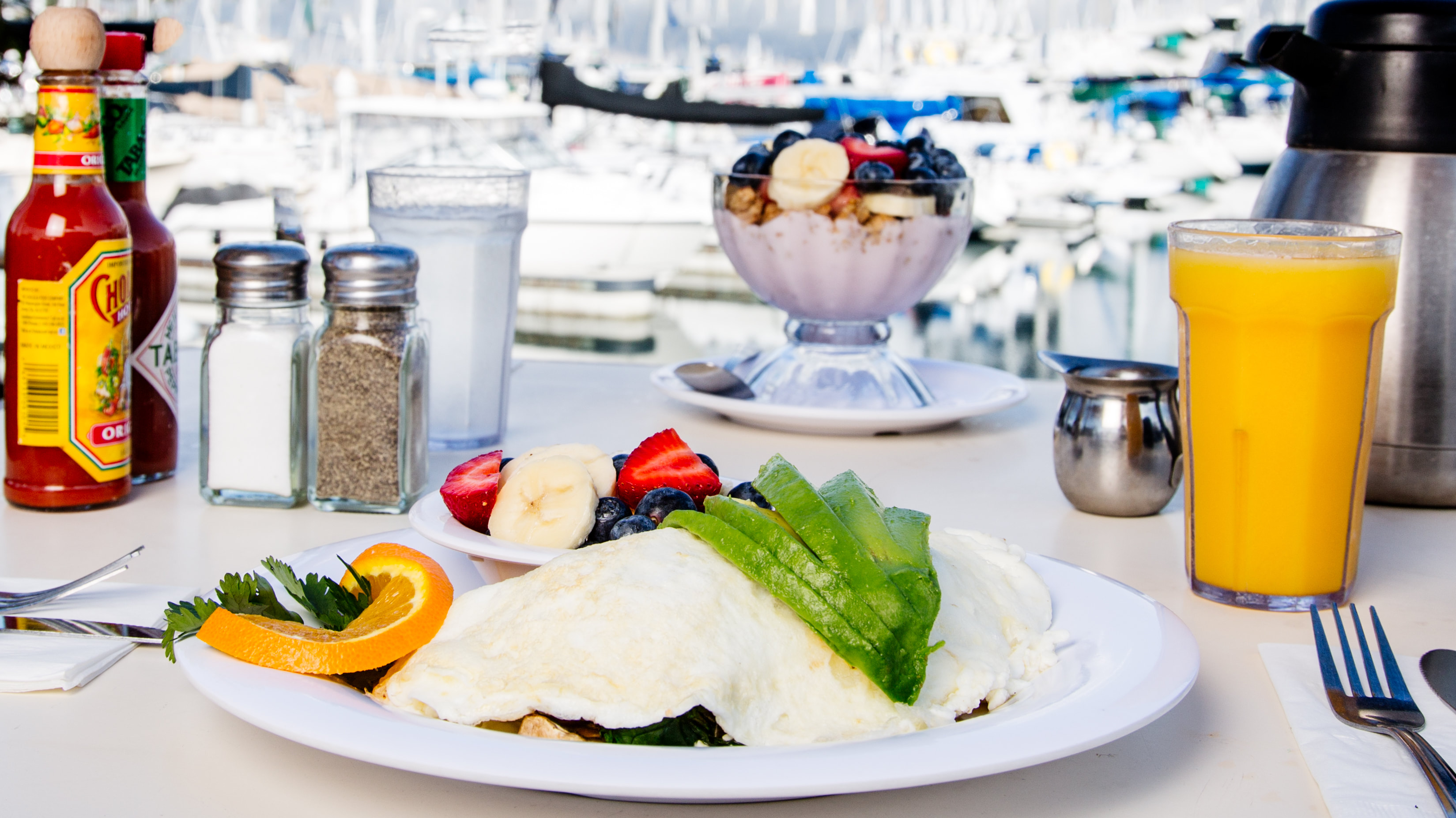 An omelet, fruit and orange juice served in front of boats at Alamitos Bay Marina