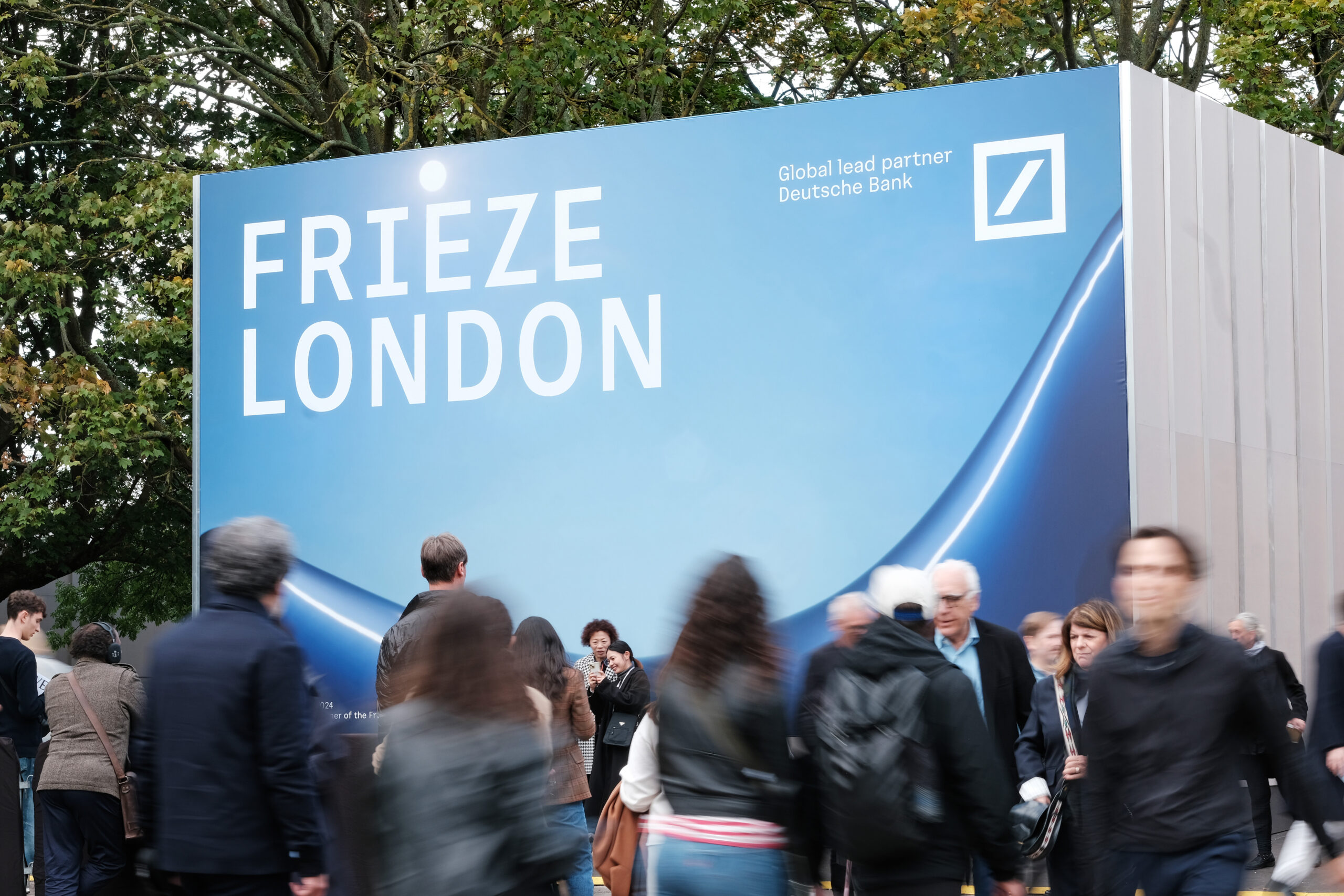 Visitors gathered beneath artworks at Frieze London 2024
