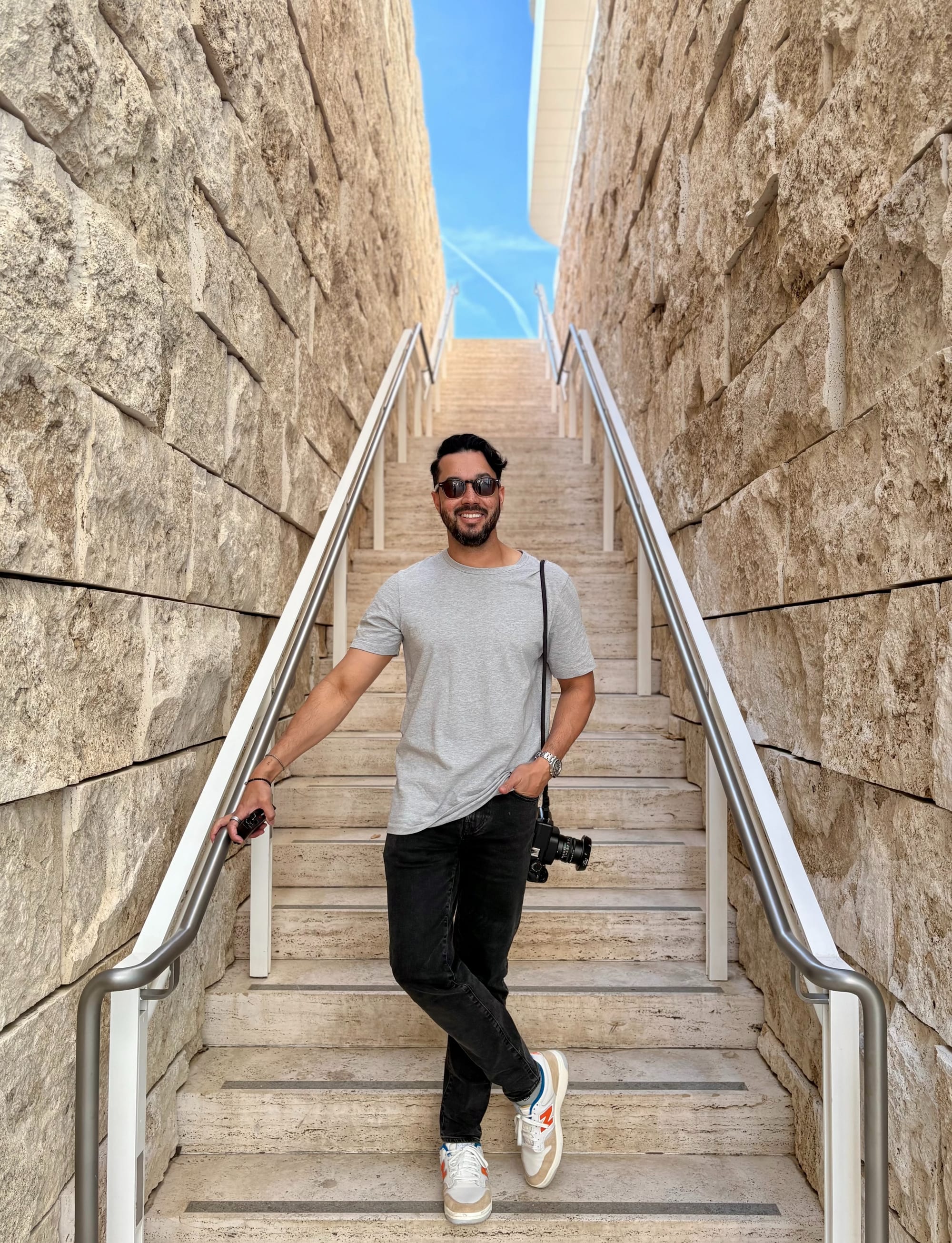 Scott Burgess standing on stone steps with a camera over his shoulder