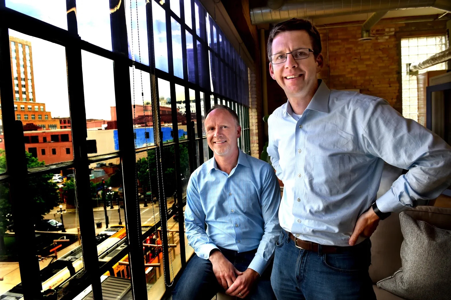 Chip House seated beside Scott Burns in a sunlit downtown St. Paul office
