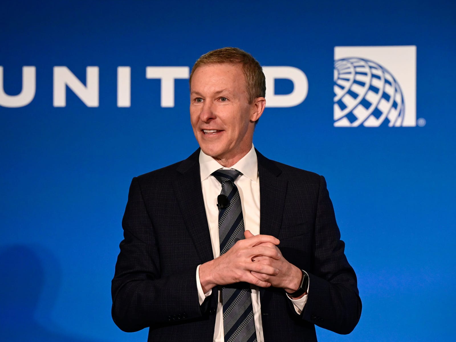 Scott Kirby speaking in front of blue United Airlines branding