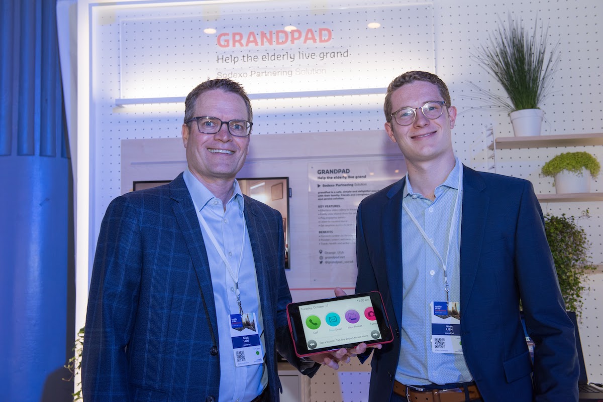 Scott Lien, left, and his son Isaac showing a GrandPad tablet at an event