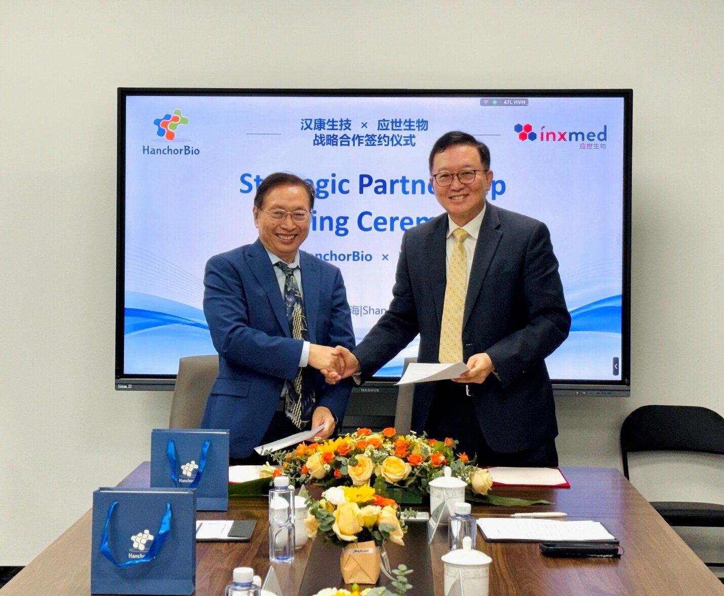 Scott Liu at left shakes hands with InxMed founder Zaiqi Wang at a partnership signing.