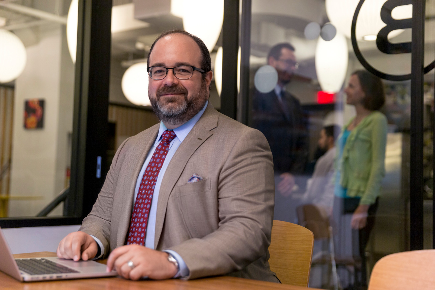 Scott Rosen seated at a laptop in a glass-walled office