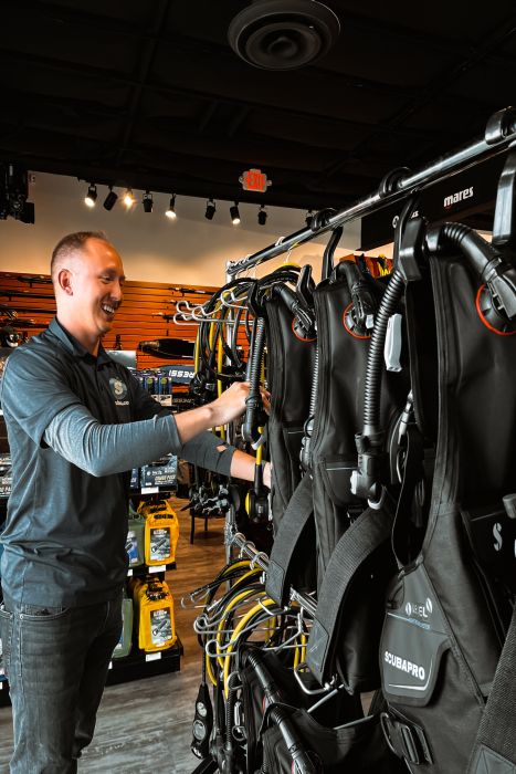 Scuba.com staff member arranging rental equipment in a dive shop