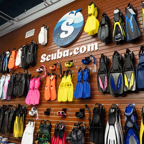 Dive fins and masks displayed beneath the Scuba.com sign in a New York store