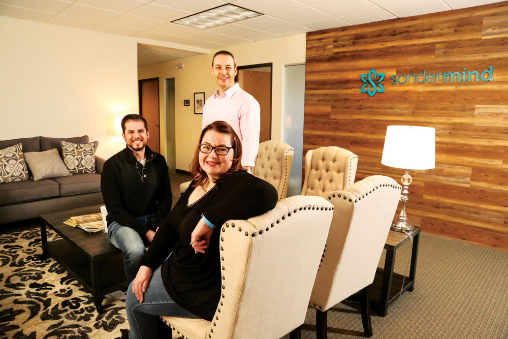 Sean Boyd, Mark Frank and Stephanie Diaz pictured together in a furnished Denver office lobby