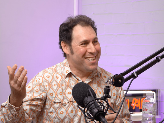 Sean Kane smiling and gesturing beside a studio microphone during his Harper James podcast interview