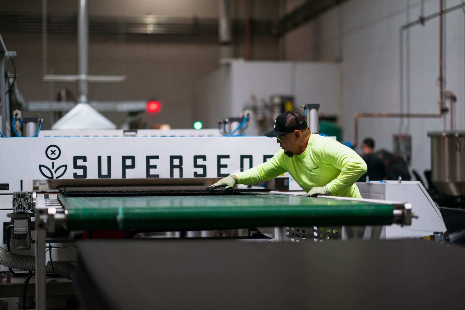 A Supersede production worker guides material across manufacturing equipment in the company factory.