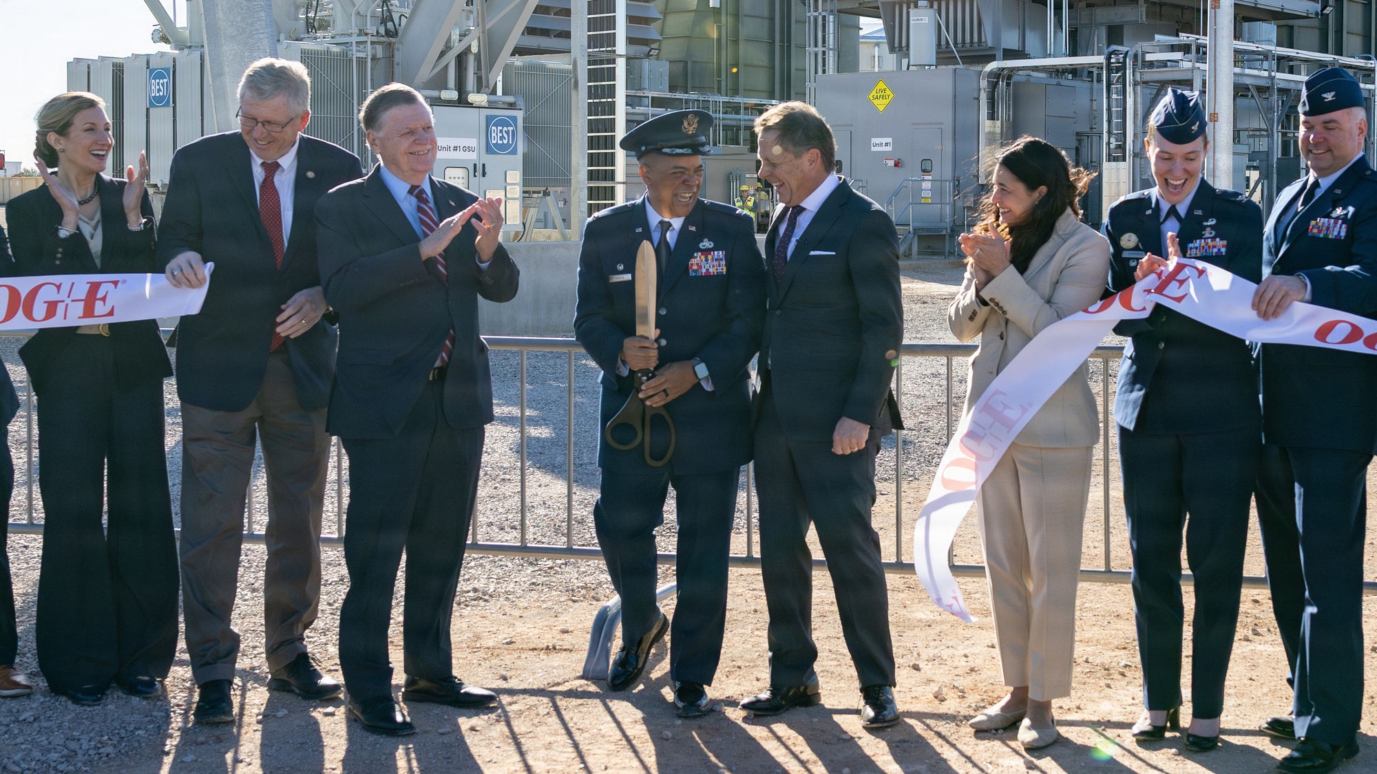 Sean Trauschke, center right, and Col. Cisco Harris celebrate after cutting the ribbon at the OG&E Tinker Power Plant.