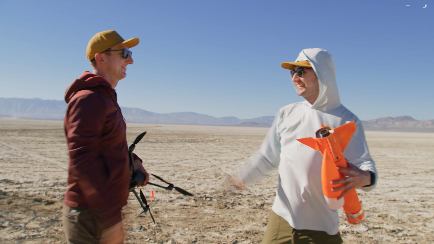 The Fischer brothers outdoors with a drone and orange rocket hardware