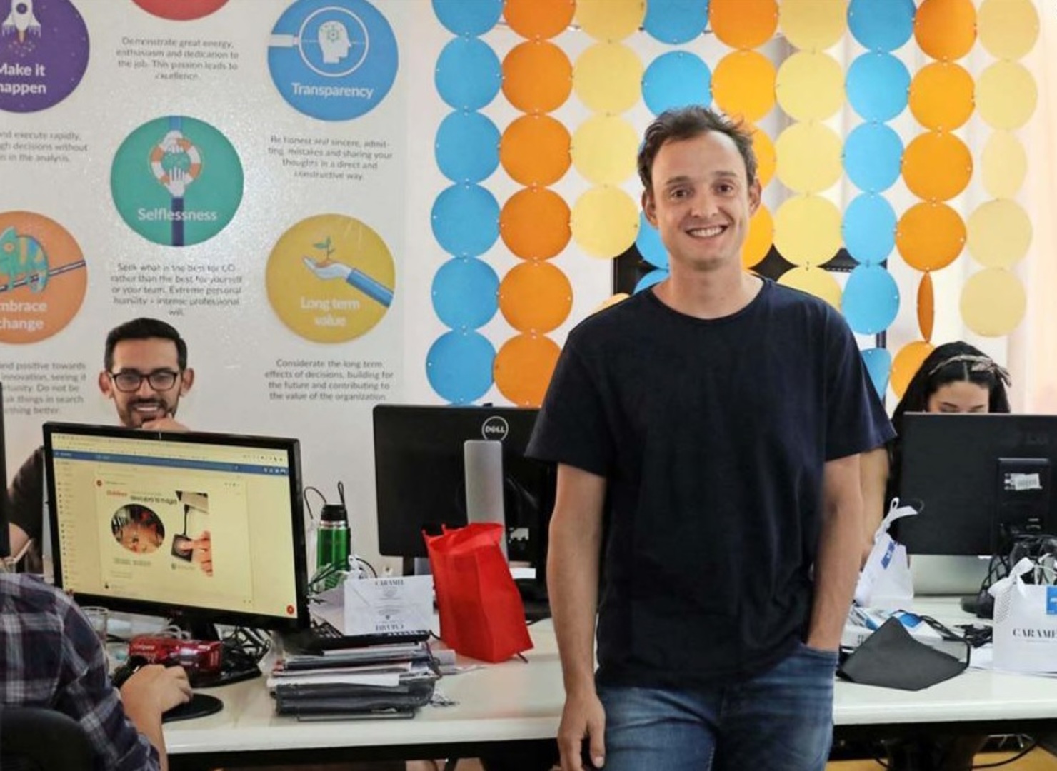 Sebastián Valin standing among colleagues and computer monitors at ComparaOnline