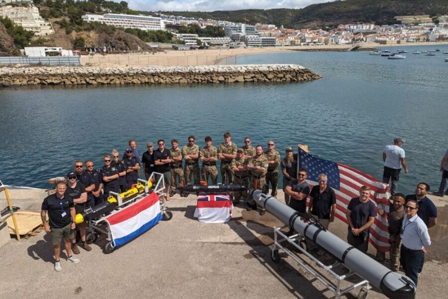 Naval teams with Dutch, British and U.S. flags beside underwater vehicles at REPMUS 2023