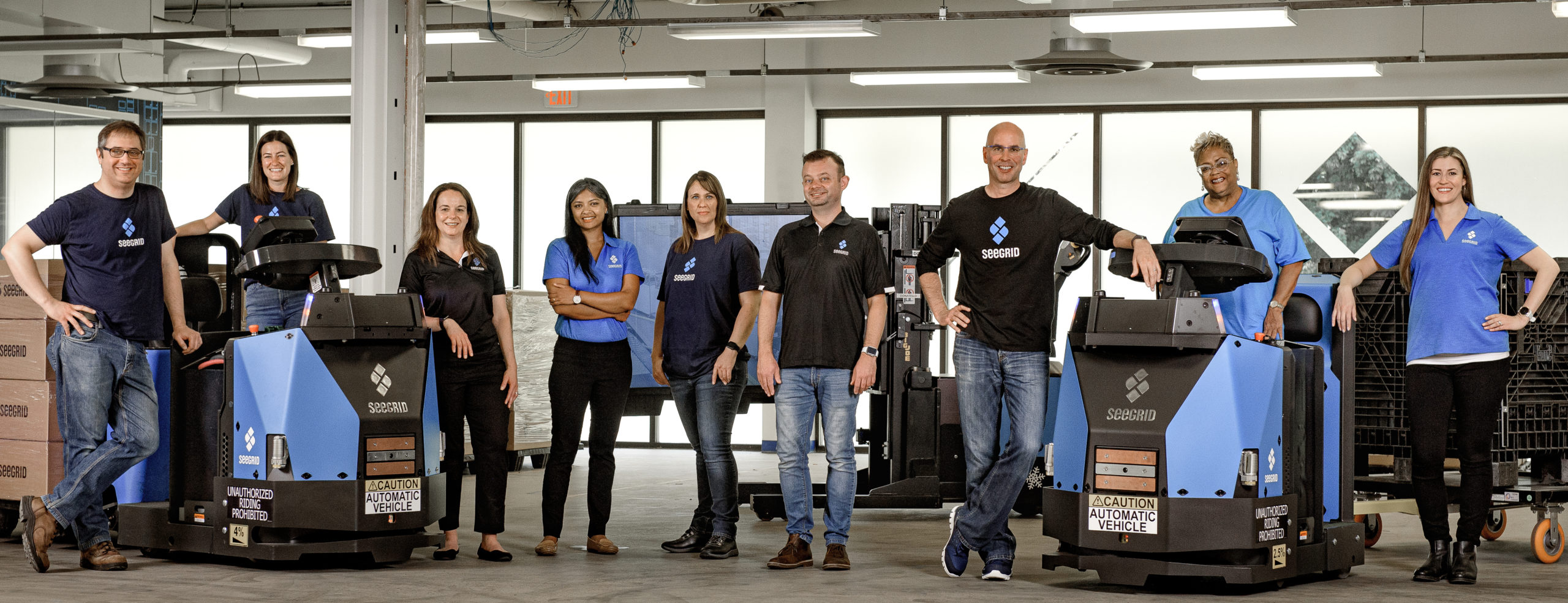 Archival Seegrid staff photograph with two blue industrial robots
