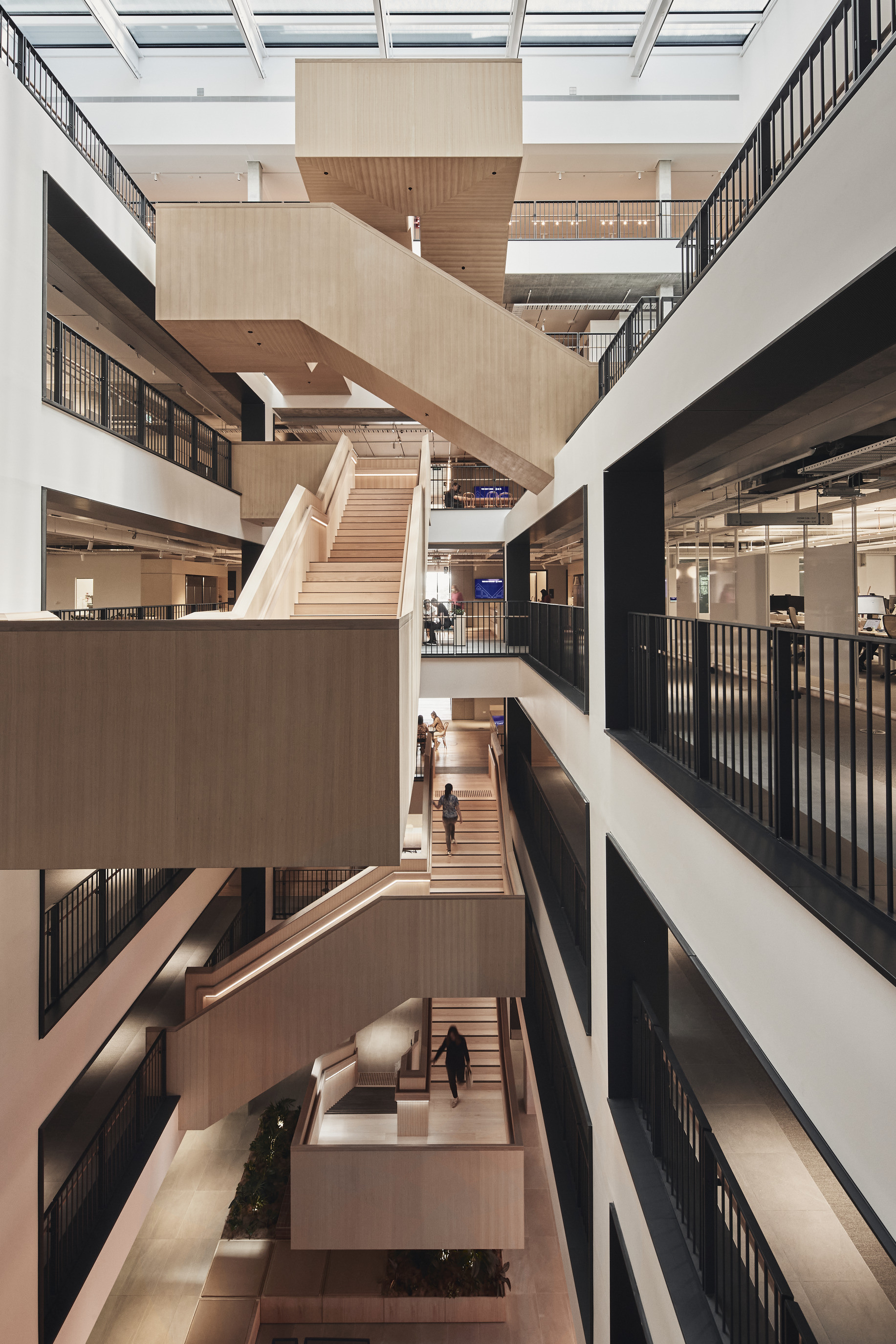 Timber staircases zigzag through the bright central atrium of SEEK’s Melbourne headquarters.