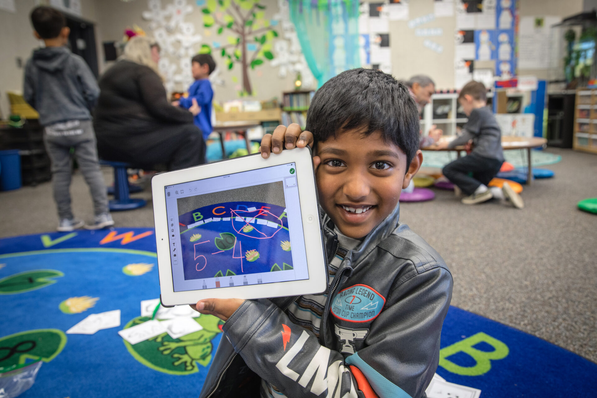 A student holding an iPad displaying an annotated classroom activity