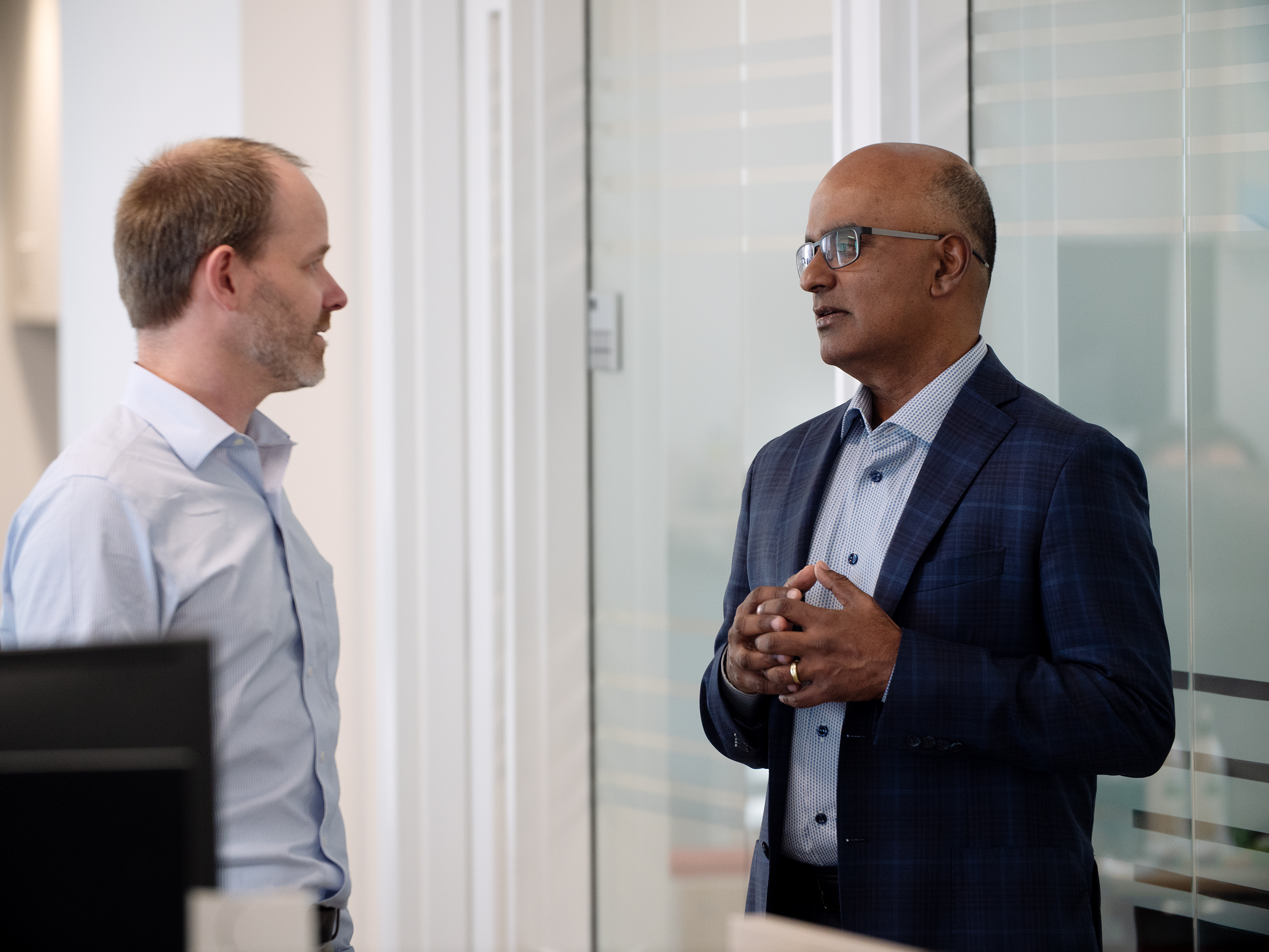 Sekar Kathiresan speaking with a colleague in a bright office