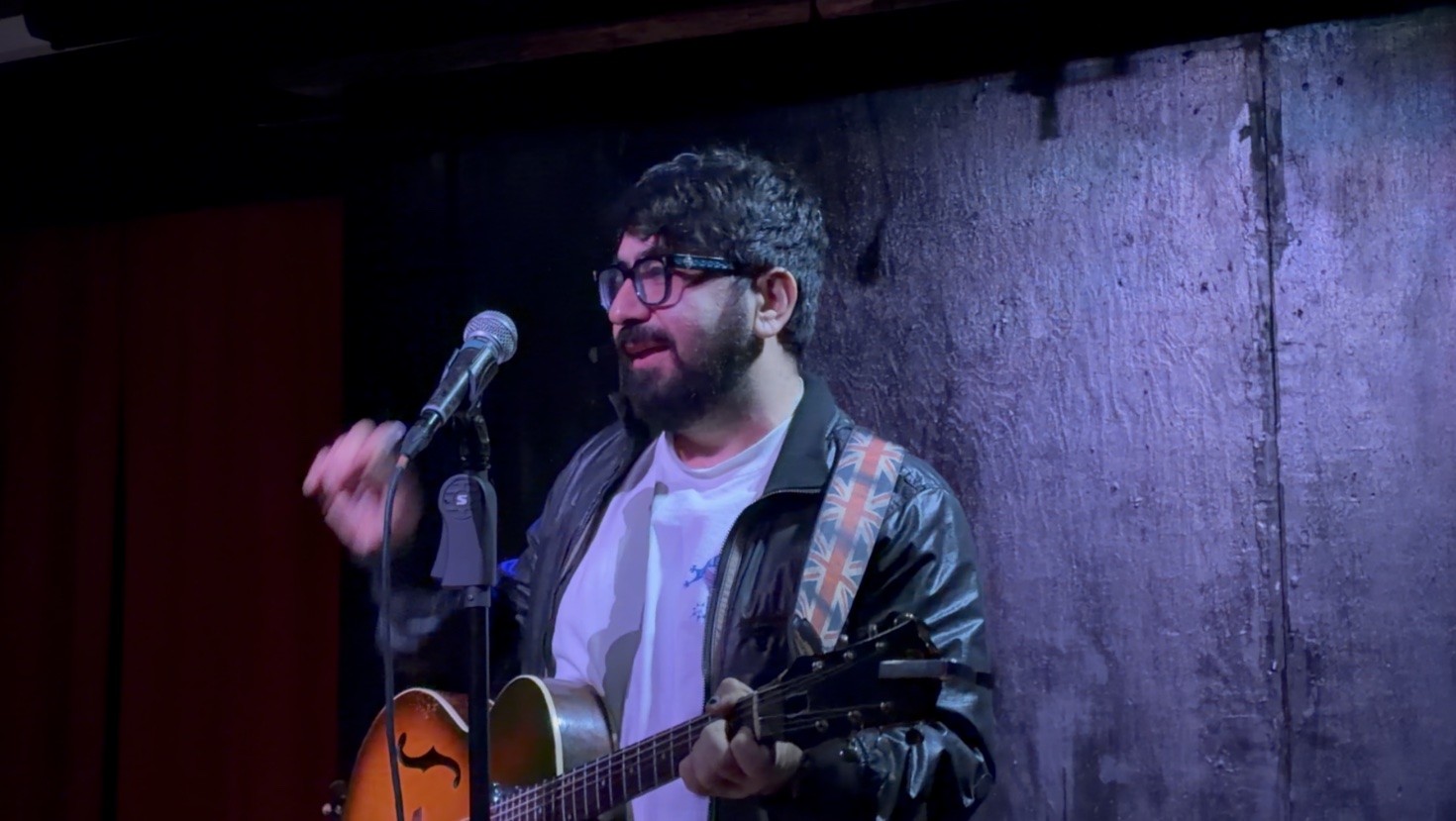 Selcuk Atli performing live with a guitar and microphone