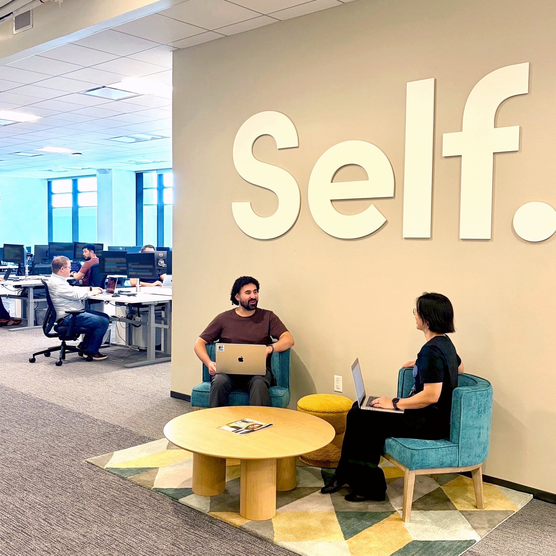 People working and talking in Self’s office, as shown on its careers page