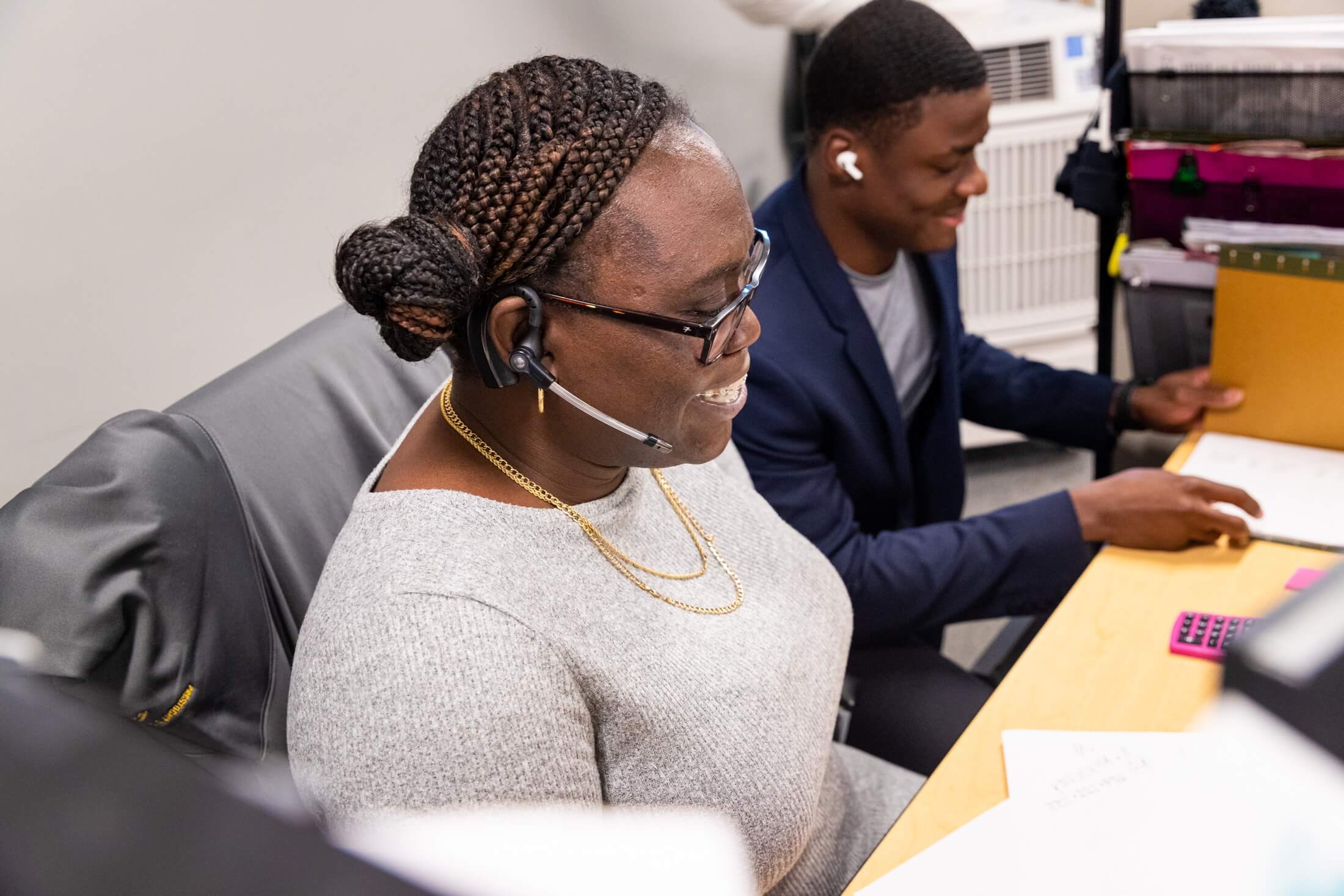 Two members of the SLS office team, one wearing a telephone headset