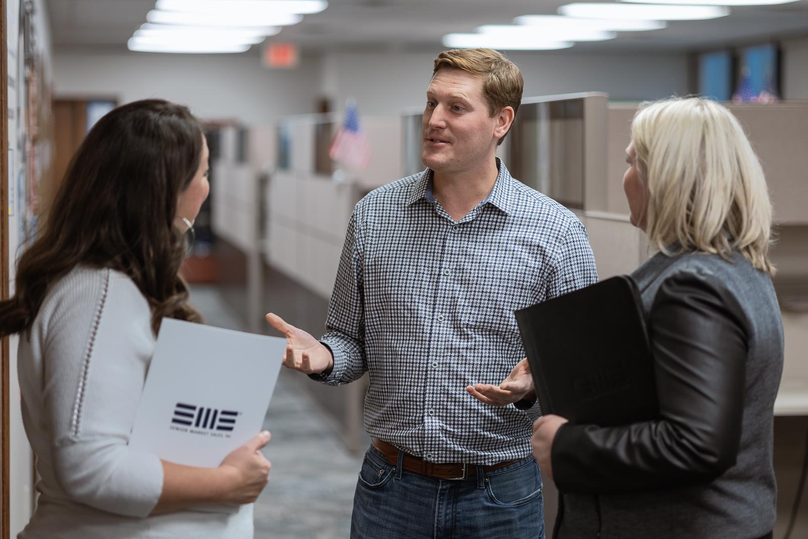 Three SMS employees talking in an office corridor